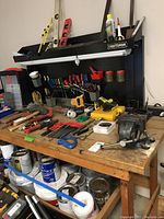 Full view of wooden workbench with various tools on top and Craftsman pegboard shelf attached at back.