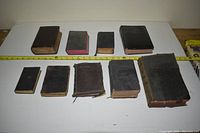 Photo of 10 assorted Bibles in various sizes, showing scale with measuring tape.