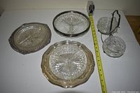 Wide shot of all six glassware items including various serving dishes and metal stand with glass bowls.
