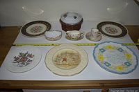 Full lot displaying four large decorative plates, two teacups with saucers, a small scalloped-edge bowl, and a wicker coaster.