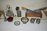 Photo of assorted silver items including cruet set, cup holders, bowl, plate, pepper mill, red dish, and two large kitchen cleavers with wooden block.