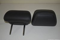 Photo of two black leather Infiniti Q50 headrests with white stitching detail and chrome mounting rods on one headrest
