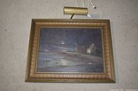 Gilt framed oil painting of moonlit beach scene with picture light attached above frame