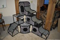 Full frontal view of the gray fabric and mesh cat tower showing multiple levels, ramps, and openings.