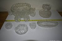 Full set showing punch bowl and six assorted crystal serving dishes on white background with measuring tape
