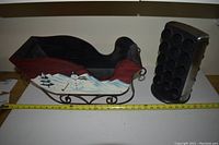 Photo of the wooden Santa sled and black Keurig pod holder on a table with measuring tape showing size