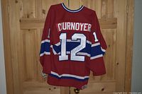 Back view of red Montreal Canadiens jersey size XL with white number 12, 'Cournoyer' nameplate and autograph on the '2'