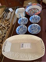 Photo showing the Lenox serving dish and five Asian bowls, four blue and one multicolor, along with some knives in the background.