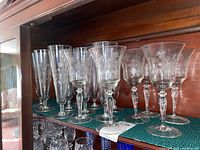 Shelved crystal stemware showing various sizes and shapes, etched floral patterns visible on several glasses.