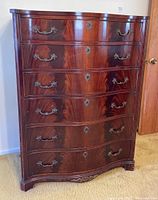 Front view of wooden dresser showing six drawers, brass handles, and keyhole escutcheons.