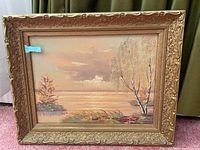 Full view of the oil painting in the ornate wooden frame, showing the landscape scene with trees, water, and cloudy sky.