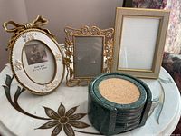 Photo showing three decorative picture frames and the round green marble coaster holder with visible cork center coasters.
