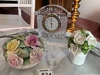 View of porcelain flowers and Waterford crystal clock on marble surface.
