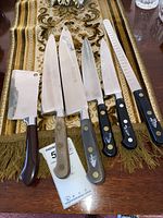 Top-down view of six knives arranged on a decorative cloth