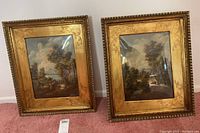 Both framed oil paintings side by side showing ornate gilt frames and landscape scenes