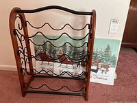 Photo showing front view of wooden and metal wine rack with two foam Christmas-themed dog placemats behind it.
