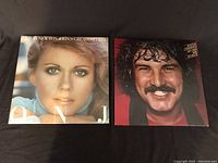 Front cover of Olivia Newton John Greatest Hits album and Burton Cummings Dreams, Nightmares & Improvisations album showing cover art and titles.