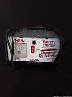 Front view of the T-612M battery charger showing the branding, 6 amp rating, ammeter, overload protection label, and power indicator light.
