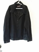 Full view of black Billabong jacket hanging on a white hanger with a half-zip front, collared neck, and long sleeves buttoned at cuffs.
