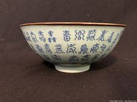 Side view of bowl showing blue Chinese characters calligraphy on white porcelain with brown rim.