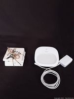 Set of 4 square ceramic coasters tied with twine on left and Philips Hue White smart light with power adapter and cable on right, both on black background.