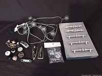 Full lot view showing string of lights, various knobs, metal hardware, decorative embellishments, and spindle pieces in box.