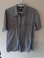 Full front view of grey dress shirt on hanger showing button front, chest pockets, and collar.