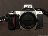 Front view of Nikon F65 camera with body cap and Nikon neck strap