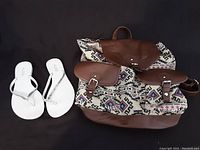 Photo showing white Aldo flip flop sandals with rhinestone straps and brown patterned shoulder bag with leather pockets and strap.
