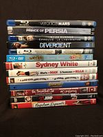 Stack of Blu-Ray and DVD movie cases including titles such as Veronica Mars, Prince of Persia, Maze Runner, Divergent, Sydney White, She's the Man, The Breakfast Club, 21 Jump Street, and Napoleon Dynamite.