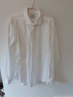 Front view of white long sleeve dress shirt on hanger, collar buttoned, showing overall shirt condition and style.
