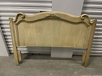 Front view of the full double headboard showing light wood finish and ornamental decorative feature centered at the top.