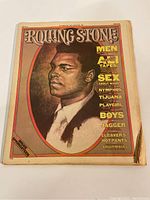 Front cover of rolling stone magazine with Muhammad Ali illustration and article headlines.
