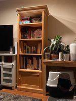Full view of the first solid wood bookshelf filled with books and decorative items, showing general condition and style.