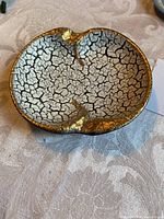 Top view of a vintage ceramic ashtray showing the crackled glaze interior with gold accents and three cigarette rests.