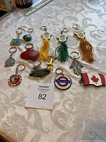 Top-view of all 12 assorted keychains spread out on a cloth surface, displaying various shapes and designs including stars, hearts, and emblematic symbols.