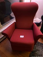Front view of dark red fabric recliner chair with wingback and padded armrests.