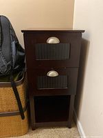 Front view of solid wood side table showing two drawers with metal pulls and open shelf below. Dark brown finish. Some wear visible.