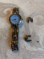 Front view of a women's Tommy Hilfiger watch with a silver metal bracelet and white dial, including three extra metal links.