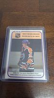 Front of 1981-82 Wayne Gretzky Record Breaker O-Pee-Chee hockey card in protective sleeve showing Gretzky in Edmonton Oilers black uniform, number 99. Highlights record assists achievement.