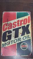 Rectangular vintage Castrol GTX Motor Oil metal sign with visible wear, rust and aging