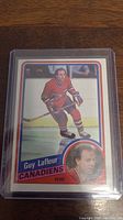 Front view of 1984-85 Guy Lafleur hockey card in protective case, showing player in Canadiens uniform and inset portrait.