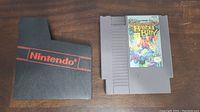 Front view of Bayou Billy NES cartridge with original sleeve next to it, showing colorful game label and sleeve's red Nintendo branding on black plastic.