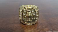 Top view of the gold-tone Stanley Cup ring showing the trophy surrounded by clear stones.