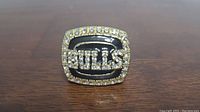 Front view of the replica championship ring showing black enamel with 'BULLS' text and rhinestone border.