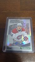 Front view of Nick Suzuki rookie hockey card showing player in Montreal Canadiens uniform with holographic finish under plastic case.