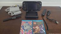 Nintendo Wii U console with GamePad controller, Wii Remote, Nunchuk, sensor bar, and power adapter on table.