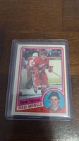 Front of Steve Yzerman rookie card showing player in Red Wings uniform skating with a goalie behind him and a headshot portrait in a circle.
