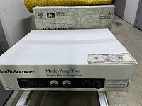 White box packaging of AudioSource Model Amp Two stereo power amplifier featuring product name, brand, front panel control graphics, and amplifier specifications.