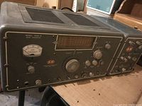 Front view showing Model 5100-B transmitter panel with frequency display, knobs, meter.